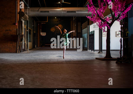 Ein junges Mädchen, das in der traditionellen Chinesischen kleid Tänze alleine in einer dunklen Halle Stockfoto