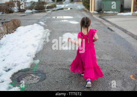 Ein kleines Mädchen in einem fancy dress Struts stolz hinunter eine verschneite Straße Stockfoto