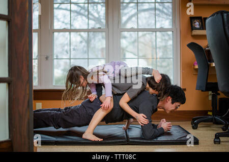 Ein Vater hält eine Ganzkörperstütz mit zwei Kinder auf seinem Rücken Blocklagerung Stockfoto