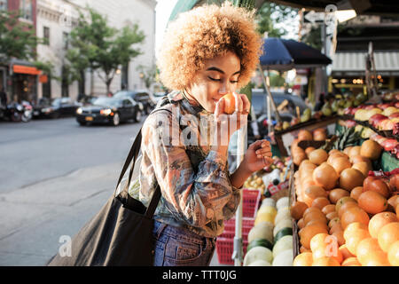 Frau riechen frische Orange am Marktstand Stockfoto