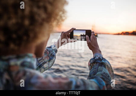 7/8 Bild der Frau fotografieren Meer durch Smart Phone Stockfoto