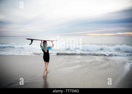 Ansicht der Rückseite des weiblichen Surfer, Surfbrett auf dem Kopf, während auf dem Weg zum Meer auf Delray Beach Stockfoto