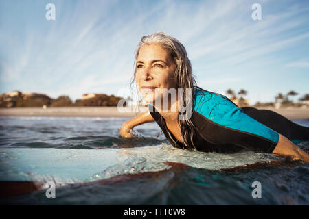 Reife Frau weg schauen beim Surfen auf Meer Stockfoto