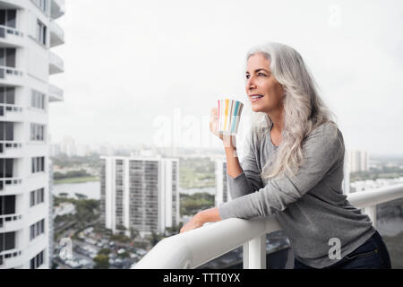 Nachdenklich, reife Frau Kaffee im Stehen auf dem Balkon Stockfoto