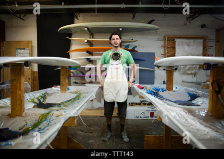 Portrait von zuversichtlich männlichen Arbeitnehmer steht man inmitten Surfbretter in Werkstatt Stockfoto