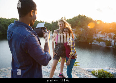 Junger Mann fotografieren Freunde durch sofortige Kamera während der Ferien Stockfoto