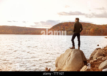 Rückansicht des Menschen stehen auf Felsen am Seeufer Stockfoto