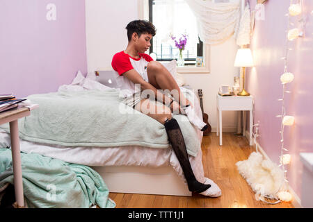 Behinderte Frau das Tragen von Socken, während auf dem Bett zu Hause sitzen Stockfoto