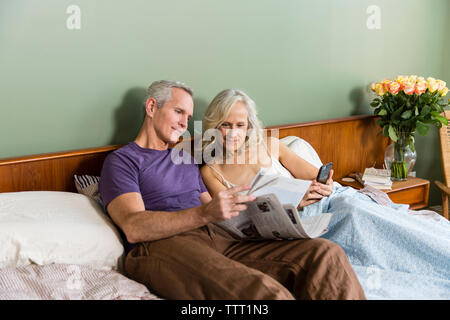 Paar lesen Zeitung, während er auf das Bett zu Hause. Stockfoto