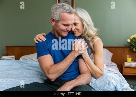 Liebevollen Mann mit Frau Hand beim Sitzen auf dem Bett zu Hause. Stockfoto