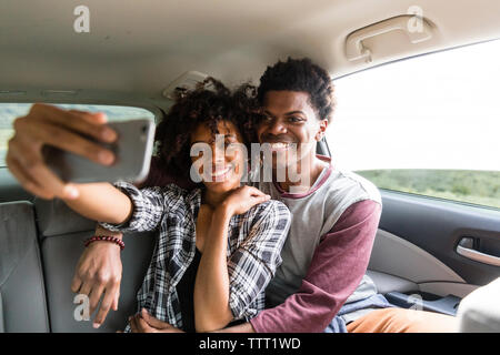 Brautpaar nehmen Selfie unterwegs im Auto Stockfoto