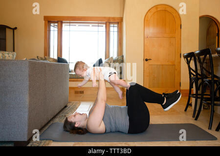 Seitenansicht der Mutter mit Sohn während des Trainings auf der Trainingsmatte zu Hause Stockfoto