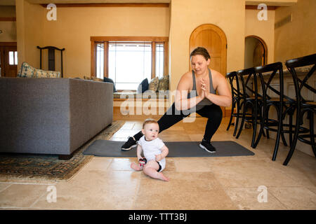 Die ganze Länge der Mutter Ausübung auf trainingsmatte, während Sohn spielen zu Hause Stockfoto