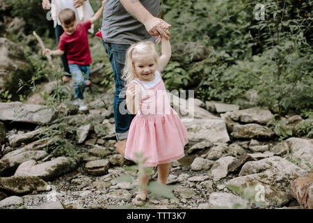 Niedrige Abschnitt der Eltern Wandern mit Kindern auf Felsen im Wald Stockfoto
