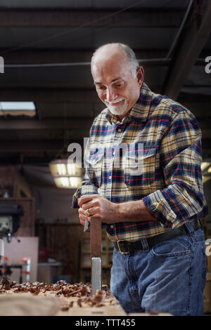Ältere Arbeitnehmer rasieren Holzbrett in Werkstatt Stockfoto