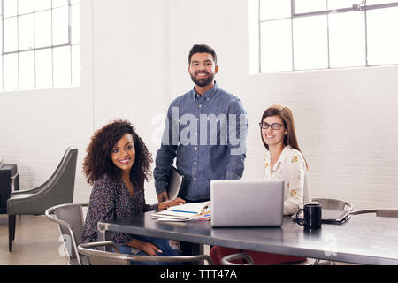 Portrait der zuversichtlichen Lächeln Geschäft Leute am Tisch im Büro Stockfoto