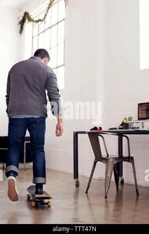 Ansicht der Rückseite des Geschäftsmann skateboarding in kreative Büro Stockfoto