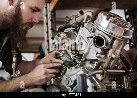 Zugeschnittenes Bild der Mechaniker arbeiten am Motorrad Motor im Shop Stockfoto