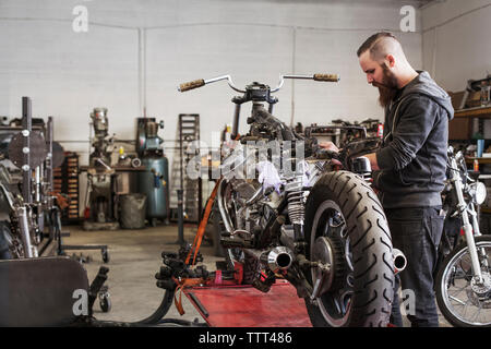 Ernsthafte Mechaniker arbeiten am Motorrad an Werkstatt Stockfoto