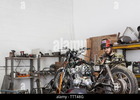 Ernsthafte Mechaniker arbeiten am Motorrad an Werkstatt Stockfoto