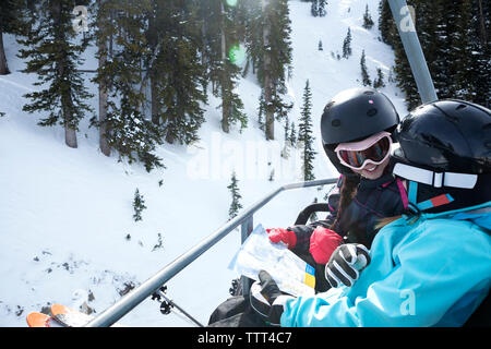 Hohe Betrachtungswinkel der Mädchen lesen Karte beim Reiten am Skilift Stockfoto