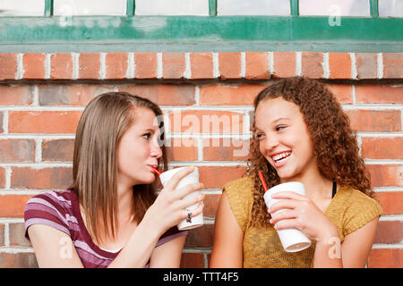 Freunde genießen, Getränk, während sie gegen die Mauer sitzen Stockfoto