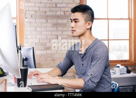 Geschäftsmann, der im Büro am Desktop-Computer arbeitet Stockfoto