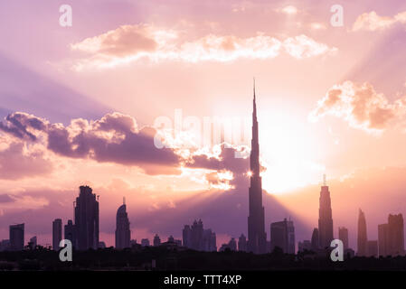 Silhouette Burj Khalifa und Wolkenkratzer gegen bewölkter Himmel bei Sonnenuntergang Stockfoto