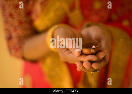 Mittelteil der Frau in Sari holding Diya während Diwali Stockfoto