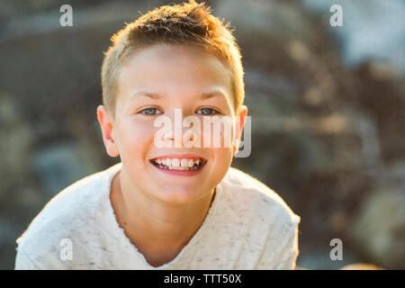 Close-up Portrait von niedlichen glückliche Junge sitzt im Freien Stockfoto