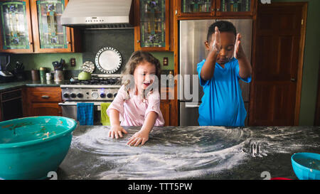 Jungen und Mädchen spielen mit Mehl in der Küche Stockfoto