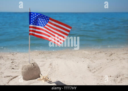 Amerikanische Flagge mit Sandburg am Strand Stockfoto