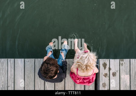 Ansicht von oben der Geschwister sitzen auf Pier über den See Stockfoto