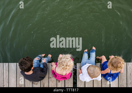 Ansicht von oben der Geschwister sitzen auf Pier über den See Stockfoto