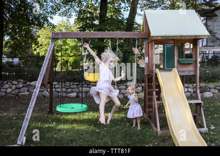 Schwestern spielen auf Schaukeln auf dem Spielplatz Stockfoto