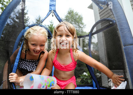 Schwestern lachend in Wasser Kampf auf Trampolin im Sommer Stockfoto