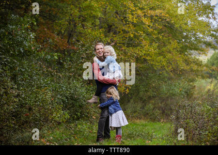 Vater lächelnd an Kamera mit zwei Töchtern zusammen in Holz glücklich Stockfoto