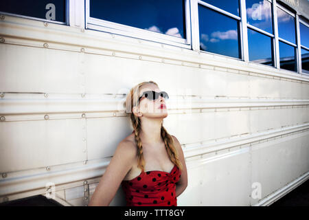 Frau mit Sonnenbrille lehnte sich auf weißen Bus Stockfoto