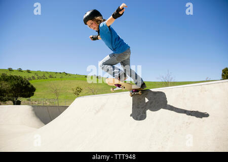 Low Angle View der Boy skateboarding auf Rampe gegen den klaren blauen Himmel Stockfoto