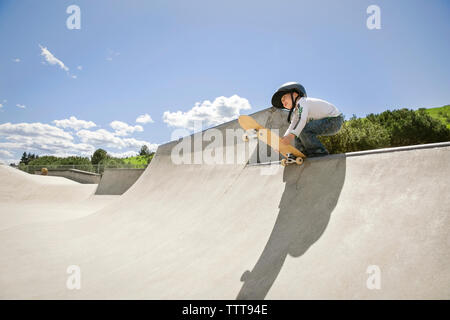 Low Angle View der Boy holding Skateboard Rampe gegen den blauen Himmel Stockfoto