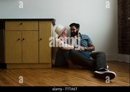 Glückliches Paar romancing, während auf dem Boden von Wand zu Hause sitzen Stockfoto