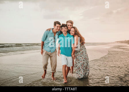 Portrait von Happy Geschwister am Strand gegen Himmel bei Sonnenuntergang Stockfoto