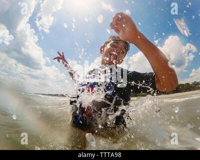 Low Angle View der Teenager schwimmen im Meer gegen bewölkter Himmel Stockfoto