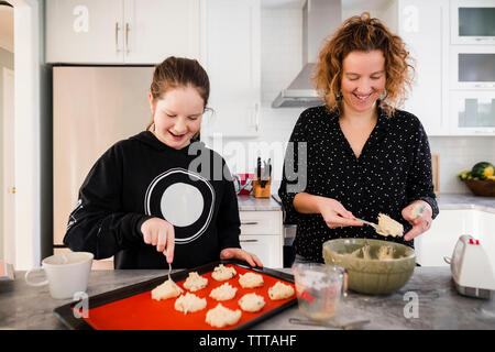 Mutter mit Tochter, Teig auf Backblech in der Küche zu Hause. Stockfoto