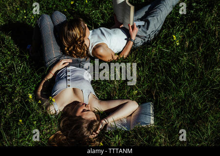 Zwei junge Mädchen und er liegt im Felde ein Buch lesen. Stockfoto