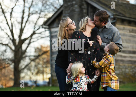 Eltern küssen beim Stehen mit Kindern im Hof Stockfoto