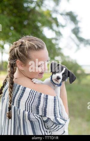 Mädchen mit Abholung Schwänze lächelnd an einen Hund mit schlappohren Stockfoto