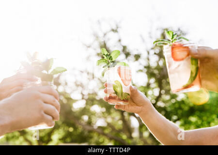 Zugeschnittenes Bild von Freunden toasten mojito Gläser im Hof Stockfoto