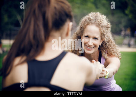 Gerne weibliche Freunde stretching Während stretching Hände halten im Park Stockfoto