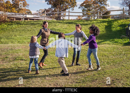 Lehrer spielen mit Studenten auf Feld während der Exkursion Stockfoto